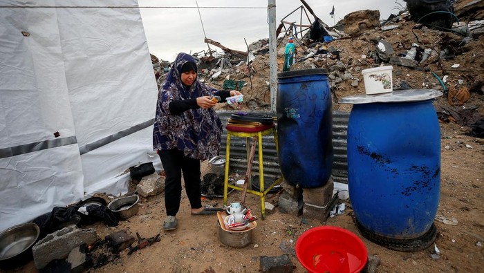 A Palestinian woman collects laundry outside her shelter, set up near the rubble of her house, on a rainy day, amid a ceasefire between Israel and Hamas, in Jabalia refugee camp in the northern Gaza Strip February 11, 2025. REUTERS/Mahmoud Issa     TPX IMAGES OF THE DAY