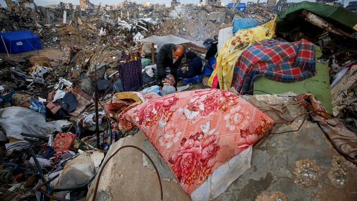 Kondisi Warga Gaza Berjuang Hadapi Musim Dingin A Palestinian woman collects laundry outside her shelter, set up near the rubble of her house, on a rainy day, amid a ceasefire between Israel and Hamas, in Jabalia refugee camp in the northern Gaza Strip February 11, 2025. REUTERS/Mahmoud Issa TPX IMAGES OF THE DAY
