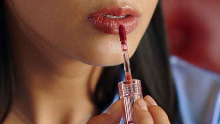 Header with woman applying red liquid lipstick
