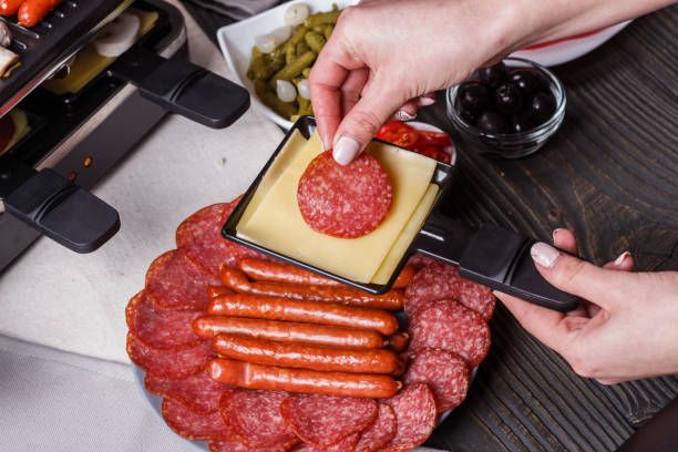 young woman is preparing a traditional Swiss cheese raclette.