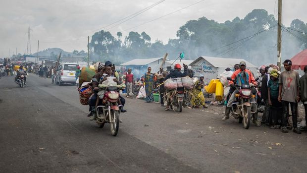 Orang-orang berkendara melewati warga Kongo yang mengungsi akibat bentrokan baru-baru ini antara pemberontak M23 dan Angkatan Bersenjata Republik Demokratik Kongo (FARDC), bersiap meninggalkan kamp dan kembali ke rumah setelah diperintahkan oleh pemberontak M23 untuk mengosongkan kamp di pinggiran Goma, Republik Demokratik Kongo, 12 Februari 2025. (REUTERS/Stringer)