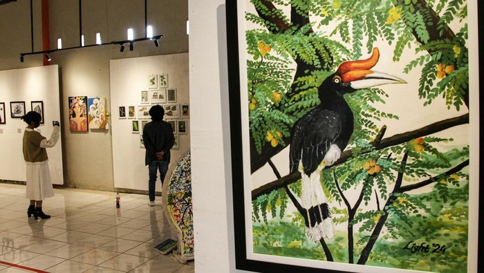Pengunjung mengamati lukisan yang dipajang pada pameran Nostalgia Kalimantan di Galeri Lawu, Palangka Raya, Kalimantan Tengah, Jumat (14/2/2025). Pameran yang diikuti 23 perupa Kota Palangka Raya tersebut menggambarkan tentang nostalgia Kalimantan yang menampilkan keindahan alam dan kekayaan budaya Pulau Borneo. ANTARA FOTO/Auliya Rahman/tom.