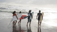 Pengunjung membawa papan selancar atau surfing saat mengikuti sesi latihan di Pantai Parangtritis, Bantul, DI Yogyakarta, Kamis (13/2/2025).