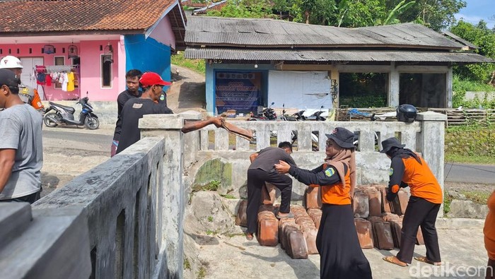 Warga dan petugas gabungan gotong royong membongkar rumah warga yang rusak akibat pergerakan tanah.