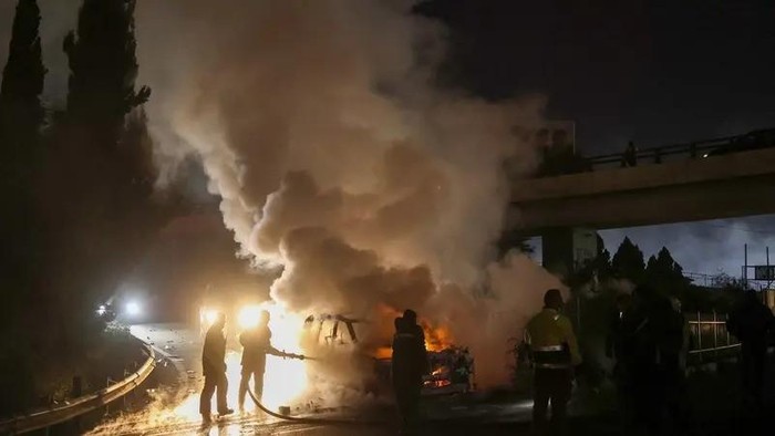 Firefighters extinguish a burning UNIFIL vehicle, set ablaze by Hezbollah supporters, on the road leading to Beirut’s airport on February 14, 2025. (AFP)