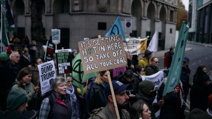 Protesters hold up placards as they gather for a combined March for Global Climate Justice, organized by the Cimate Justice Coalition, in London on November 16, 2024, 