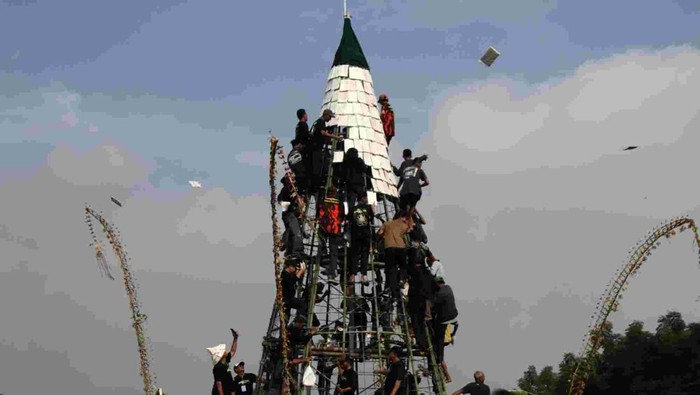 Panitia membagikan tempe saat ruwat desa di Lapangan Desa Sedenganmijen, Krian, Sidoarjo, Jawa Timur, Minggu (16/2/2025). Tradisi ruwat desa dengan membuat tumpeng tempe setinggi 12 meter yang diselenggarakan setiap tahun menjelang bulan suci Ramadhan tersebut menjadi ajang sedekah dan sebagai bentuk rasa syukur para perajin tempe kepada Tuhan YME atas limpahan rezeki. ANTARA FOTO/Umarul Faruq/YU