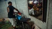 Seorang kru mempersiapkan sepeda motor untuk roda gila yang disaksikan anak-anak.