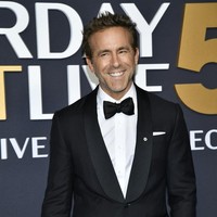 Ryan Reynolds tampil elegan dalam setelan jas hitam, lengkap dengan dasi kupu-kupu. Senyum semringah menghiasi wajahnya kala berpose di depan kamera. Foto: Evan Agostini/Invision/AP