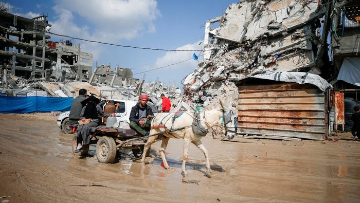 Palestinians sit next to a fire among the rubble of buildings destroyed during the Israeli offensive, amid a ceasefire between Israel and Hamas, at Jabalia refugee camp, northern Gaza Strip, February 17, 2025. REUTERS/Mahmoud Issa     TPX IMAGES OF THE DAY     REFILE - CORRECTING FROM 