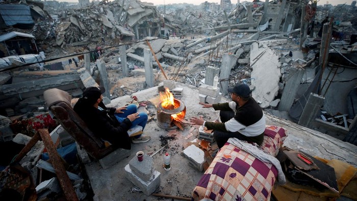 Palestinians sit next to a fire among the rubble of buildings destroyed during the Israeli offensive, amid a ceasefire between Israel and Hamas, at Jabalia refugee camp, northern Gaza Strip, February 17, 2025. REUTERS/Mahmoud Issa     TPX IMAGES OF THE DAY     REFILE - CORRECTING FROM 