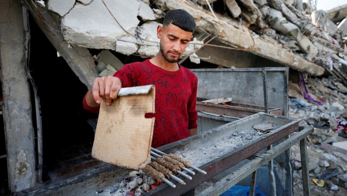 Palestinians sit next to a fire among the rubble of buildings destroyed during the Israeli offensive, amid a ceasefire between Israel and Hamas, at Jabalia refugee camp, northern Gaza Strip, February 17, 2025. REUTERS/Mahmoud Issa     TPX IMAGES OF THE DAY     REFILE - CORRECTING FROM 