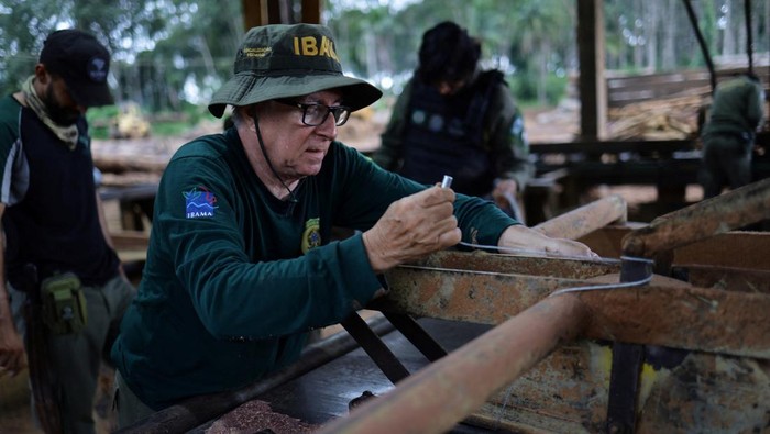 Agents of the ICMBio (Chico Mendes Institute for Biodiversity Conservation) and Brazilian Institute for the Environment and Renewable Natural Resources (IBAMA) inspect logs seized from the Amazon rainforest during an operation to combat deforestation, at a sawmill in Nova California, Rondonia State, Brazil February 8, 2025. REUTERS/Ueslei Marcelino