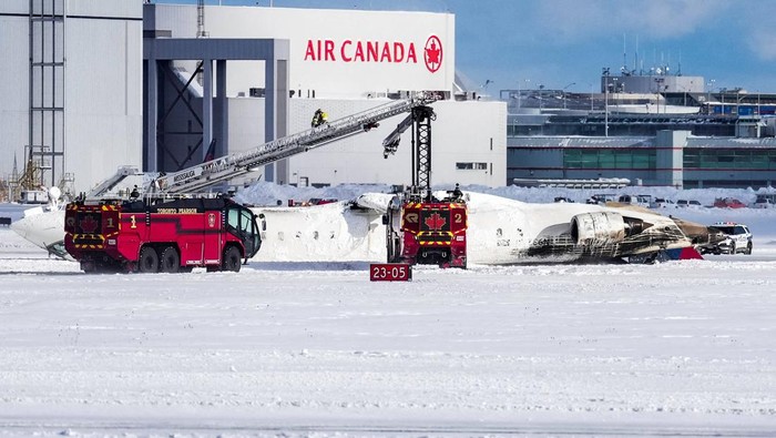 Emergency responders walk around a plane on a runway, after a plane crash at Toronto Pearson International Airport in Mississauga, Ontario, Canada February 17, 2025. REUTERS/Cole Burston