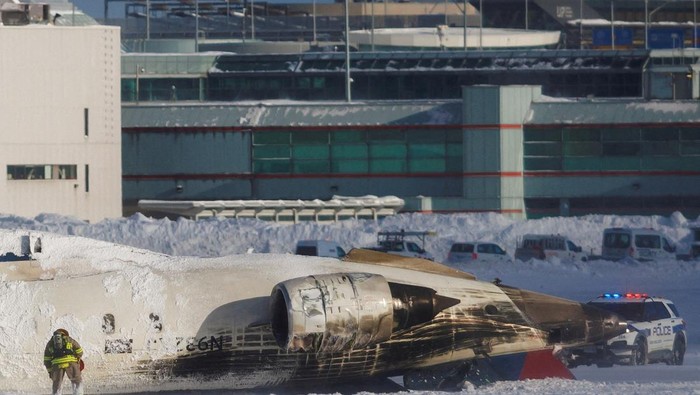 Emergency responders walk around a plane on a runway, after a plane crash at Toronto Pearson International Airport in Mississauga, Ontario, Canada February 17, 2025. REUTERS/Cole Burston