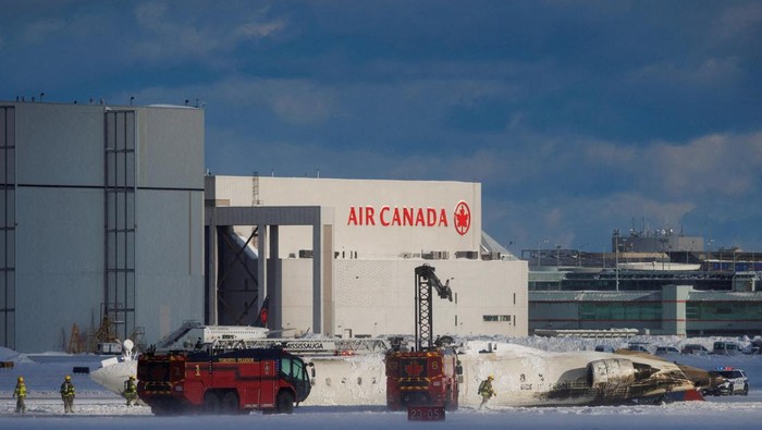 Emergency responders walk around a plane on a runway, after a plane crash at Toronto Pearson International Airport in Mississauga, Ontario, Canada February 17, 2025. REUTERS/Cole Burston