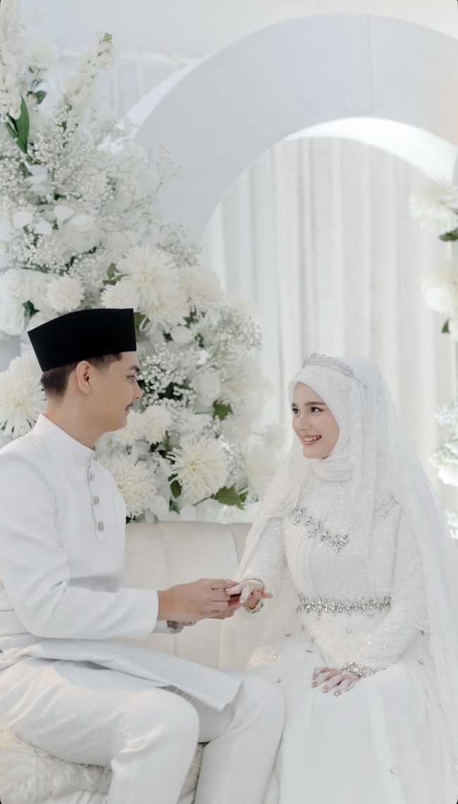 Yasmine dan suaminya tampil dalam balitan busana serba putih. Demikian pula dengan dekorasinya yang bertabur dengan bunga-bunga yang juga bernuansa putih. Foto: Instagram/@yxsmine.ow