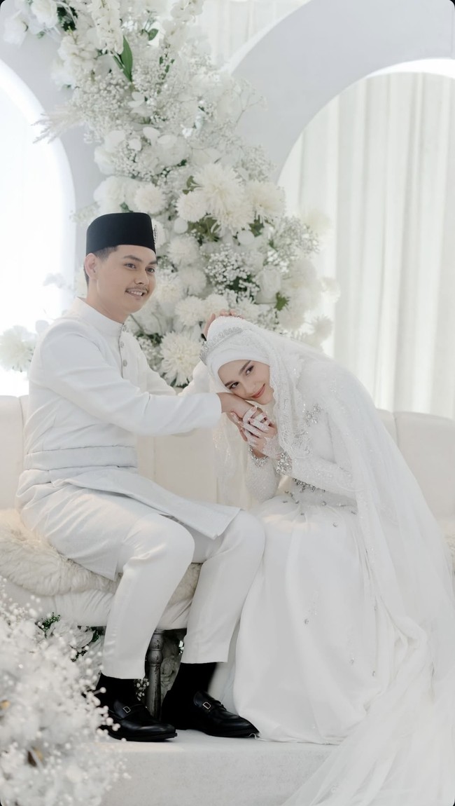 Yasmine tampil cantik dan anggun mengenakan busana pengantin tertutup lengkap dengan hijab. Gaun pengantin lengan panjang yang dikenakannya itu tampak dipercantik dengan payet dan batu-batu kristal. Menambah keanggunannya, sebuah veil panjang tampak menghiasi hijab di kepalanya. Foto: Instagram/@yxsmine.ow