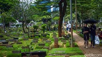 Peziarah datang bersama keluarganya, berjalan masuk menapaki pinggir makam untuk sampai ke makam keluargannya.  