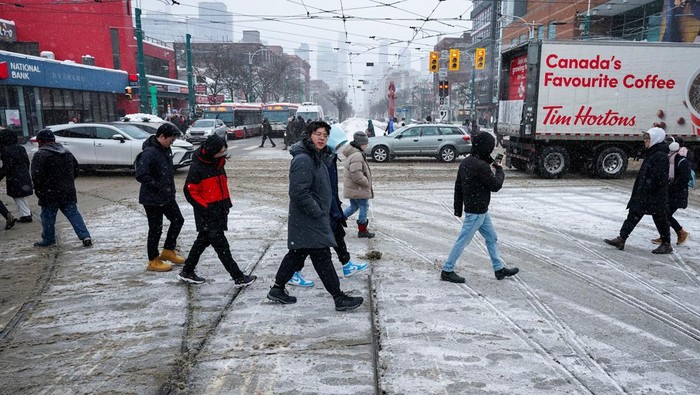 Badai Musim Dingin yang Parah Melanda Kanada People walk down a snow covered street during a snowstorm in Toronto, Ontario, Canada February 15, 2025. REUTERS/Arlyn McAdorey