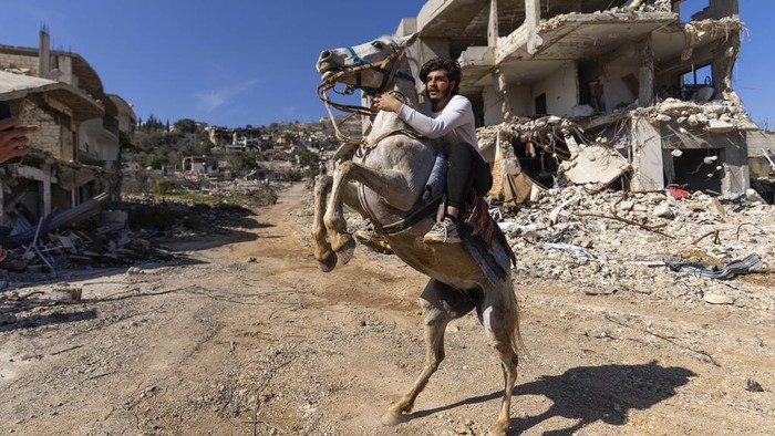 A Lebanese man rides his horse in a village destroyed by an Israeli air and ground offensive, in the town of Kfar Kila, southern Lebanon, Tuesday, Feb. 18, 2025. (AP Photo/Hassan Ammar)
