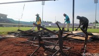 Petugas membersihkan besi papan iklan yang hangus terbakar.
