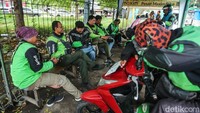 Para driver menunggu penumpang di shelter ojek online (ojol) di kawasan Stasiun Bekasi Timur, Rabu (19/2/2025). Mereka berkumpul sambil memantau orderan di smartphonenya.