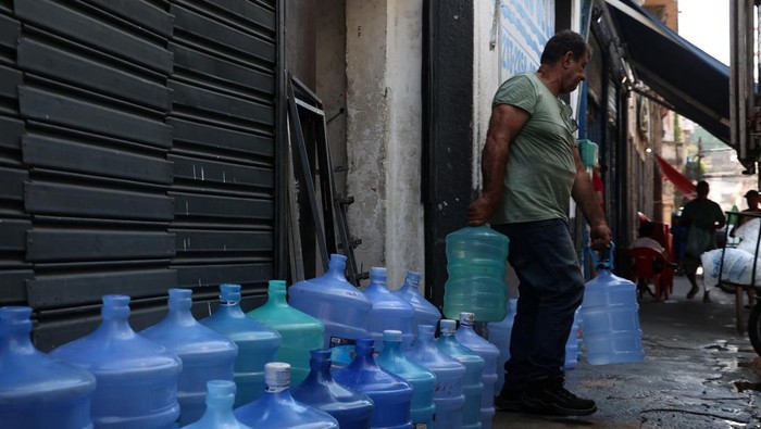 A worker carries empty gallons at a water gallons store as several neighborhoods run out of water, amid a extreme heatwave, in Rio de Janeiro, Brazil February 19, 2025. REUTERS/Aline Massuca