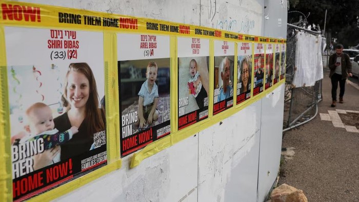 A person walks near pictures of Ariel Bibas, Shiri Bibas and Kfir Bibas, who were kidnapped during the deadly October 7, 2023 attack on Israel, in Jerusalem, February 19, 2025. REUTERS/Ronen Zvulun Purchase Licensing Rights