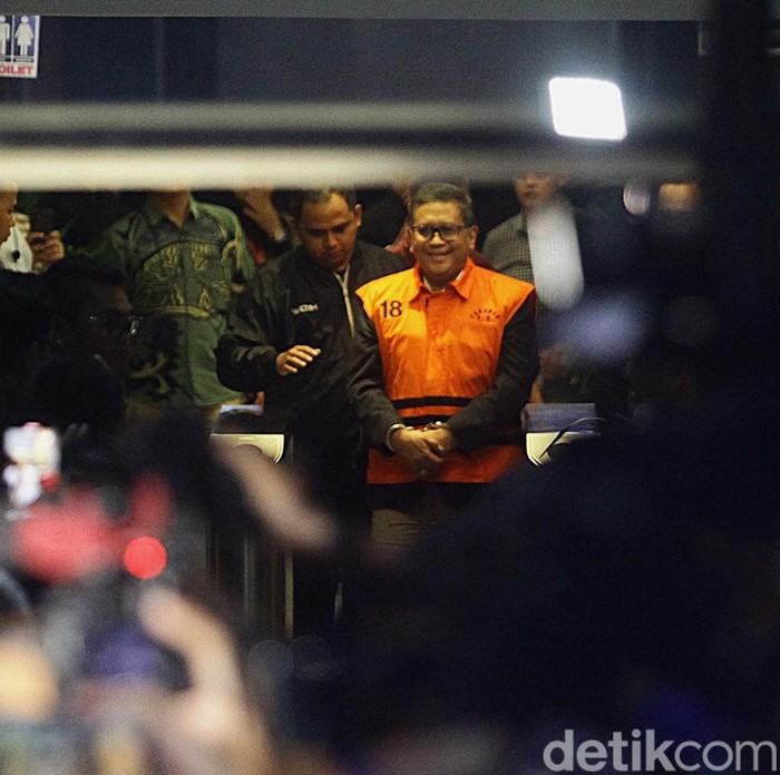 Sekjen PDI Perjuangan Hasto Kristiyanto mengenakan rompi tahanan dengan tangan terborgol saat proses penahanan di Gedung Merah Putih KPK, Jakarta, Kamis (20/2/2025). Hasto beberapa kali mengepalkan tangan dan tersenyum ke awak media. Hasto ditahan sebagai tersangka dalam kasus dugaan suap kepada komisioner KPU terkait pergantian antarwaktu (PAW) anggota DPR yang melibatkan Harun Masiku, serta perintangan penyidikan