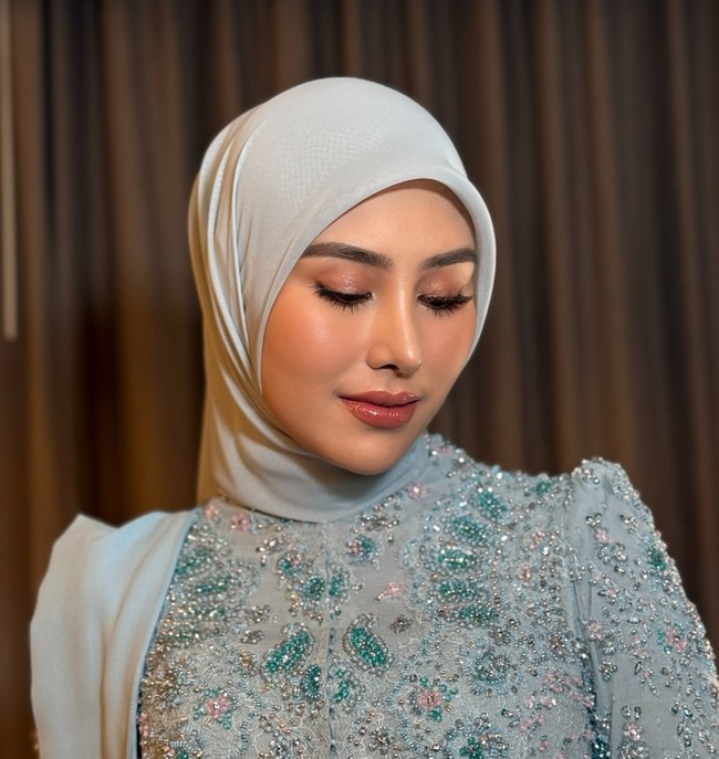 Eyeshadow berwarna coklat dihiasi dengan sedikit shimmer dipadukan dengan eyeliner dan bulu mata palsu. Mempercantik tampilan matanya, Syahnaz juga mengenakan lensa kontak berwarna coklat. Penampilannya makin fresh dan merona dengan pulasan blush on dan lipstik berwarna merah muda kecoklatan. Foto: Instagram/@ochiipramita