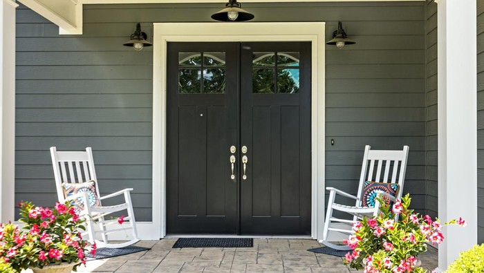 A front porch with two rocking chairs, stamped concrete floors, and double glass doors.