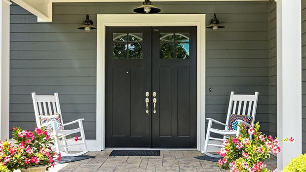 A front porch with two rocking chairs, stamped concrete floors, and double glass doors.