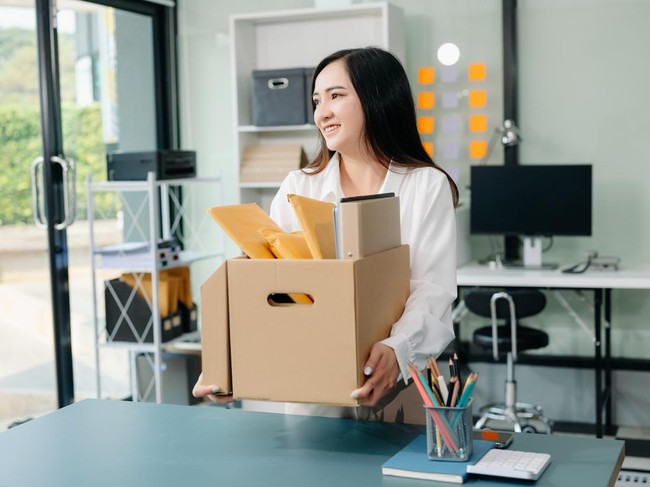 Happy and excited young beautiful Asian woman office worker celebrating her resignation, carrying her personal stuff. leaving job, changing or company.in modern office