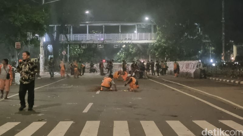 Pasukan oranye atau petugas PPSU mulai bersih-bersih di lokasi demonstrasi, 21 Februari 2025 malam. (Taufiq S/detikcom)