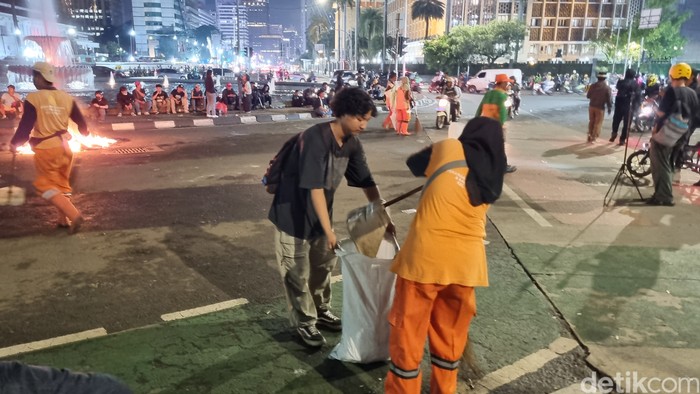 Pasukan oranye atau petugas PPSU mulai bersih-bersih di lokasi demonstrasi, 21 Februari 2025 malam. (Taufiq S/detikcom)