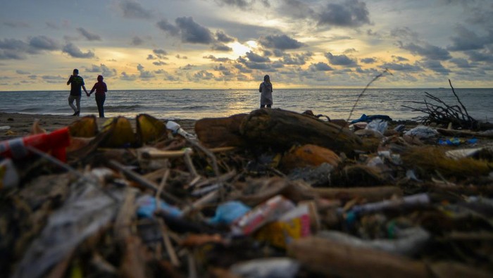 Sejumlah pengunjung berjalan di antara sampah di Pantai Purus Padang, Sumatera Barat, Jumat (21/2/2025). Sampah yang terbawa aliran sungai dari hulu kemudian sampai ke laut itu memenuhi kawasan pantai dan menimbulkan bau tidak sedap sehingga mengganggu wisatawan. ANTARA FOTO/Iggoy el Fitra/nym.