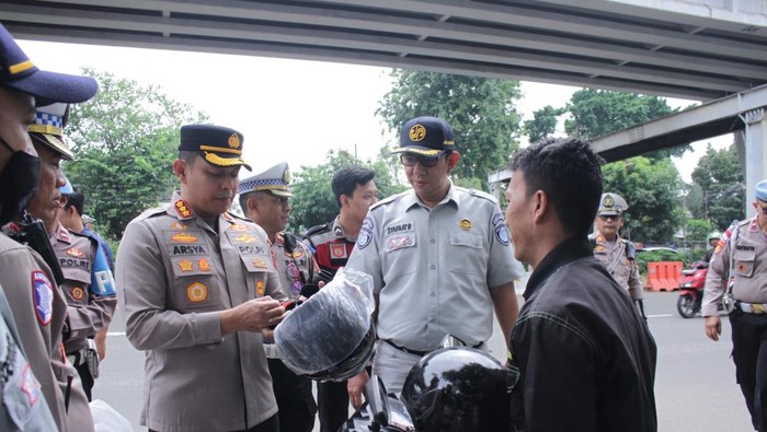 Polres Metro Jakarta Barat membagikan helm gratis kepada pengendara motor dalam rangka Operasi Keselamatan 2025