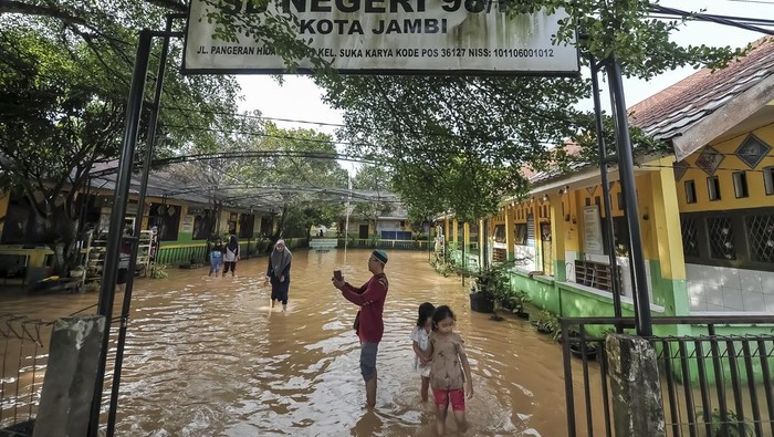 Sekolah terdampak banjir di Jambi Guru dan murid berada di halaman SDN 98 Kota Jambi yang terendam banjir luapan Sungai Kenali Asam di Suka Karya, Jambi, Jumat (21/2/2025). Aktivitas belajar mengajar 386 murid di sekolah yang telah mengalami banjir keempat dalam tahun ini tersebut terpaksa diliburkan. ANTARA FOTO/Wahdi Septiawan/foc.