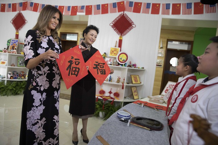 FILE - U.S. first lady Melania Trump and Chinese first lady Peng Liyuan, second right, hold up Chinese calligraphy of the character for 