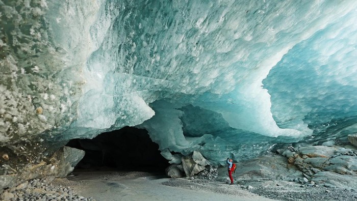 Menyusuri Dinginnya Gua Es di Swiss Hikers walk out of one of the ice caves formed by water during the summer on the tongue the Morteratsch glacier as it melts due to climate change in Pontresina near Saint Moritz in eastern Switzerland, February 21, 2025. REUTERS/Denis Balibouse