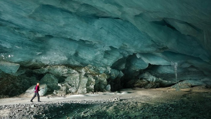 Menyusuri Dinginnya Gua Es di Swiss Hikers walk out of one of the ice caves formed by water during the summer on the tongue the Morteratsch glacier as it melts due to climate change in Pontresina near Saint Moritz in eastern Switzerland, February 21, 2025. REUTERS/Denis Balibouse