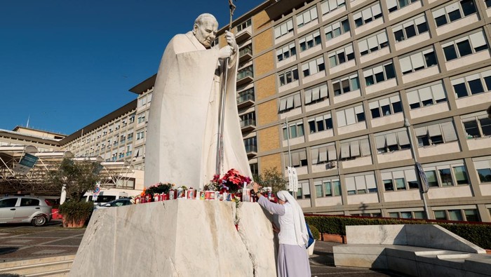 A nun stands in front of statue of the late Pope John Paul II outside the Gemelli Hospital, where Pope Francis is admitted for treatment, in Rome, Italy, February 21, 2025. REUTERS/Remo Casilli