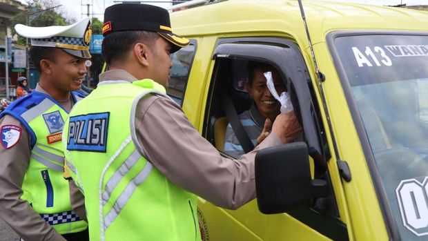 Para anggota Polres Banjarnegara membagikan helm hingga suplemen di Jalan Pemuda, Jumat (21/2/2025).