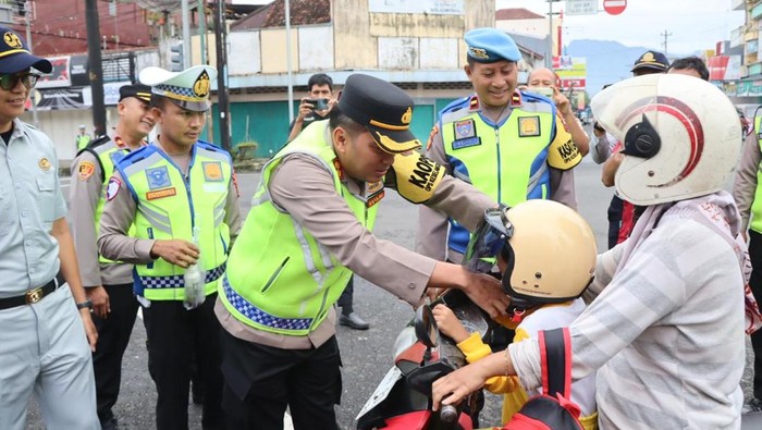 Para anggota Polres Banjarnegara membagikan helm hingga suplemen di Jalan Pemuda, Jumat (21/2/2025).