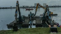 Petugas menggunakan alat berat untuk mengeruk lumpur di Waduk Pluit, Jakarta, Minggu (23/2/2025).