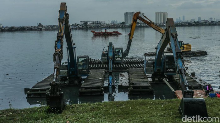 Petugas menggunakan alat berat untuk mengeruk lumpur di Waduk Pluit, Jakarta, Minggu (23/2/2025).