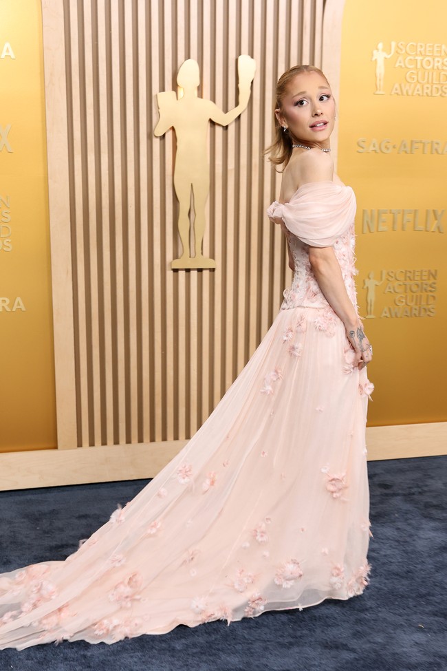 Gaun off-the-shoulder berwarna pink pucat dari Loewe menjadi pilihan Ariana Grande. Gaun dihiasi dengan aplikasi bunga yang menambah kesan feminin. (Foto: Amy Sussman/Getty Images)