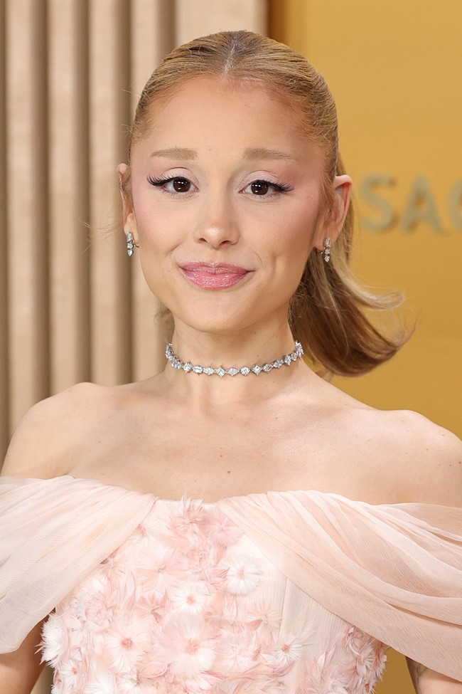 Ariana Grande menunjukkan pesonanya dengan bibir glossy berwarna pink rose dan kuncir ekor kuda yang simple. Gaya ini memberi sentuhan feminin yang sederhana tapi tetap memikat.  Foto: Getty Images