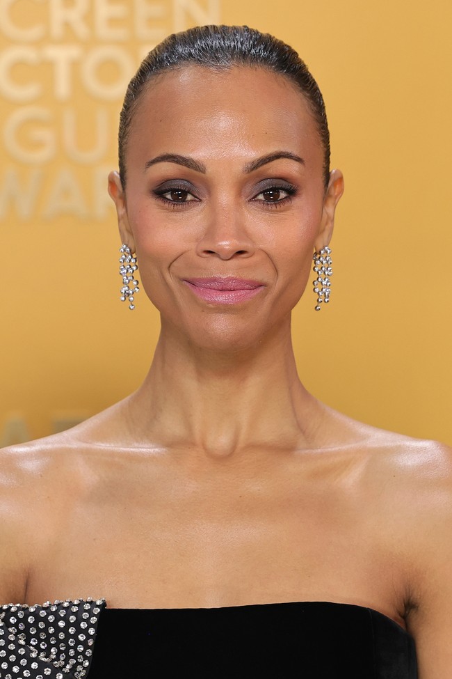 Zoe Saldana tampil anggun dengan bibir pink lembut dan mata smoky yang halus. Gaya rambutnya yang menyerupai ‘wet ballerina bun’ diciptakan oleh stylist Mara Roszak. Foto: Getty Images